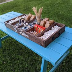 two trays filled with snacks sitting on top of a blue picnic table