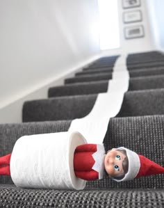 an elf is laying down on the stairs with toilet paper in it's mouth