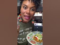 a woman holding a plate with food on it in her hand and looking at the camera