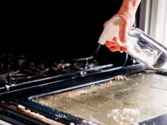 a person is cleaning the oven with a sponge and water from a spray bottle on it