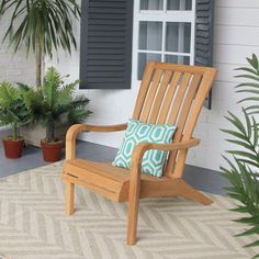 a wooden chair sitting on top of a rug in front of a window next to a potted plant