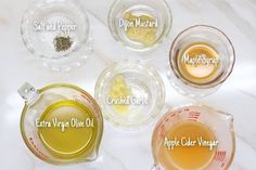 four different types of olive oil in glass bowls on a marble counter top with labels