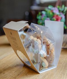 a cookie in a clear plastic bag on a wooden table next to a potted plant