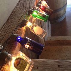 several bottles are lined up on the side of a wooden fence with lights around them