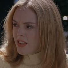 a woman with blonde hair wearing a turtle neck sweater and looking at something in the distance