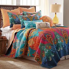 a bed with colorful comforters and pillows