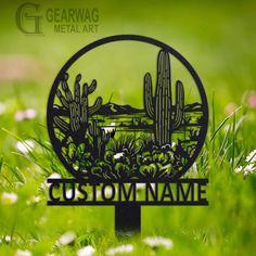 a metal sign that says custom name in front of some flowers and cactuses on the grass