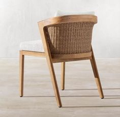 a wooden chair sitting on top of a floor next to a white wall with a plant in it