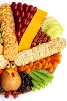 a platter with crackers, grapes, apples, cheese, nuts and turkey