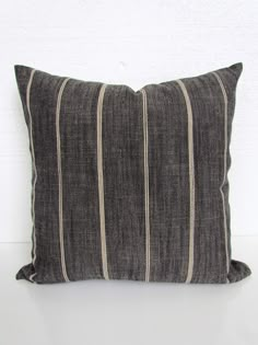 a black and white striped pillow sitting on top of a white table next to a wall