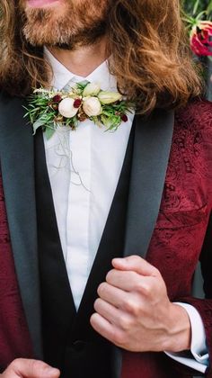 a man with long hair wearing a tuxedo and flower boutonniere