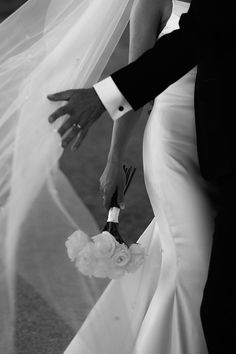 the bride and groom are walking down the aisle holding each other's hands as they hold their bouquets