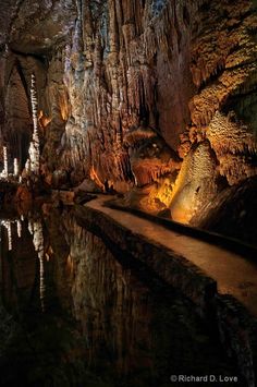 the inside of a cave is lit up with lights and reflections on the water's surface