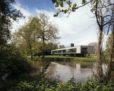 a house sitting on top of a lush green field next to a river filled with water