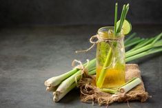 a glass jar filled with liquid next to celery stalks and lemon wedges