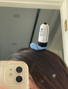 a woman taking a selfie in front of a mirror with a crocheted hat on top of her head