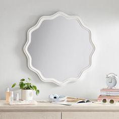 a mirror sitting on top of a wooden dresser next to a potted plant and books