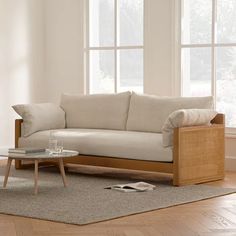 a white couch sitting on top of a wooden floor next to a table and windows