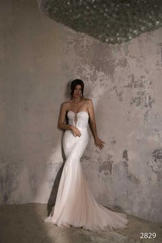 a woman in a white dress standing next to a wall