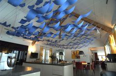 blue paper birds are suspended from the ceiling in this modern kitchen and dining room area