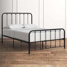 a black metal bed frame with white sheets and pillows on it, against a white wall