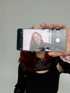 a woman taking a selfie with her cell phone in front of her face,