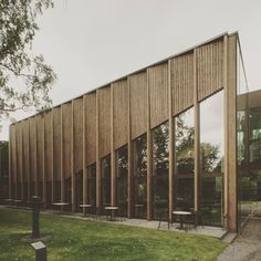 the building is made out of wood and has large windows on each side, along with tables and chairs