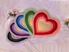 a bunch of heart shaped rugs sitting on top of a white sheet with flowers