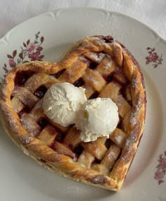 a heart shaped pie with ice cream on top sits on a floral plate, ready to be eaten