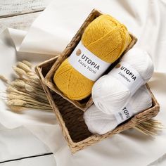 two skeins of yarn sitting in a basket on top of a white sheet