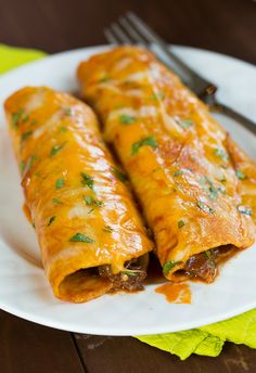 two enchiladas on a plate with a fork