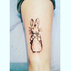 a small rabbit tattoo on the right leg, with an inked image of a bunny holding a carrot