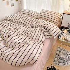 an unmade bed with striped sheets and pillows