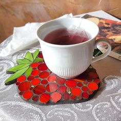 a cup of tea sitting on top of a table next to a book and magazine