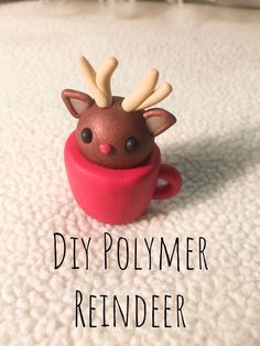 a small toy reindeer sitting in a cup on top of a white blanket with the words diy polymer reindeer