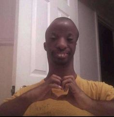 a man is smiling and holding his hands together in front of the camera while wearing a yellow t - shirt