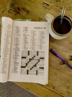 a crossword puzzle book next to a cup of coffee