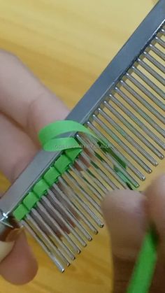 a person is holding a comb with green ribbon on it and scissors in front of them