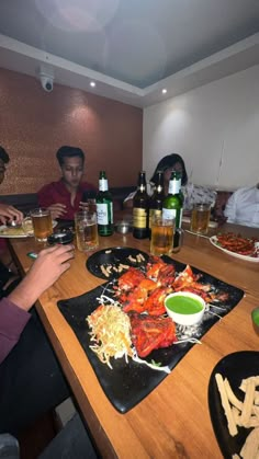 several people sitting around a table with plates of food and beer in front of them