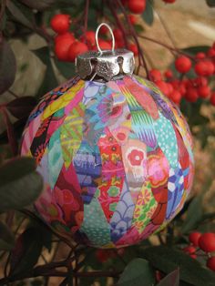 a colorful ornament hanging from a tree filled with red berries and green leaves