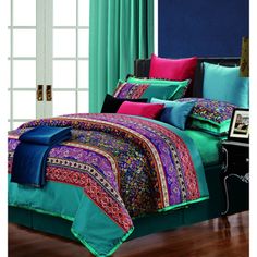 the bed is covered with colorful comforters and pillows