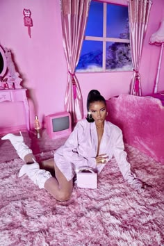 a woman sitting on top of a bed in a pink room