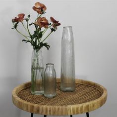 three vases on a table with flowers in them