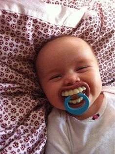 a baby laying on top of a bed with a pacifier in it's mouth