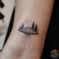 an alien ship tattoo on the ankle with trees and stars in the sky above it