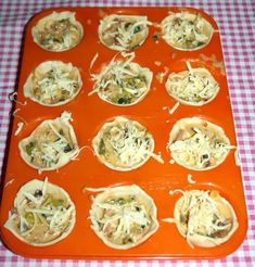 an orange tray filled with mini pizzas on top of a checkered table cloth