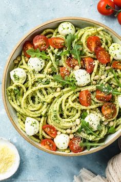 a bowl full of pesto pasta with tomatoes and mozzarella