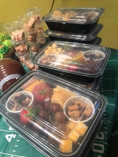 several plastic containers filled with food sitting on top of a green table cloth next to a football