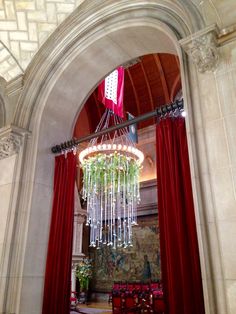 a chandelier hanging from the ceiling in a room with red drapes and curtains