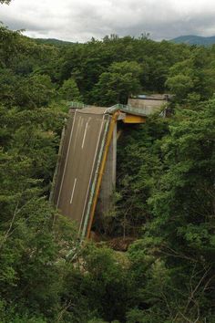 an overhead view of a road in the middle of some trees and hills with cars driving on it